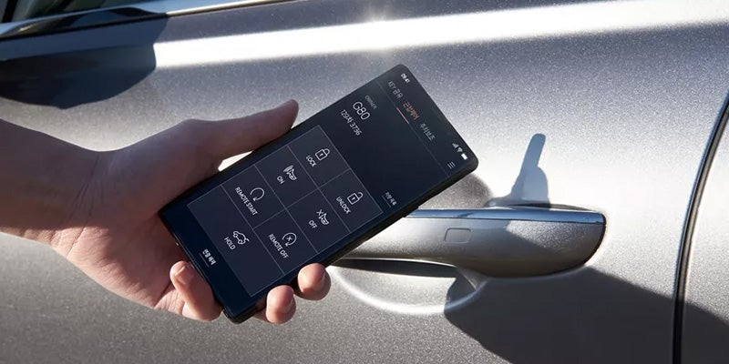 A person unlocking their all new 2024 Genesis model vehicle with an app on their phone. - Genesis of Baton Rouge, LA