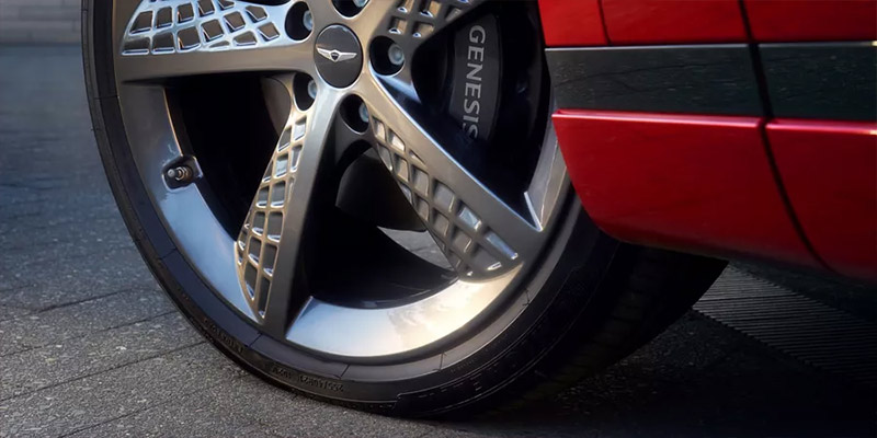 The dirver side front wheel and tire of an all-new red 2025 Genesis Electrified GV70. - Genesis of Baton Rouge, LA